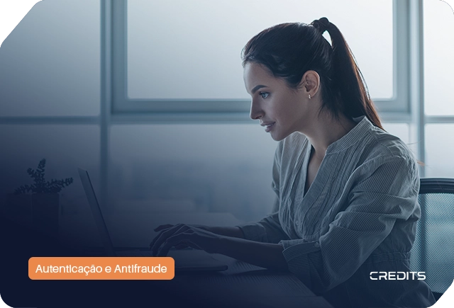 Profissional focada utiliza computador em escritório corporativo para processos de autenticação e antifraude digital, com marca 'CREDITS' visível.