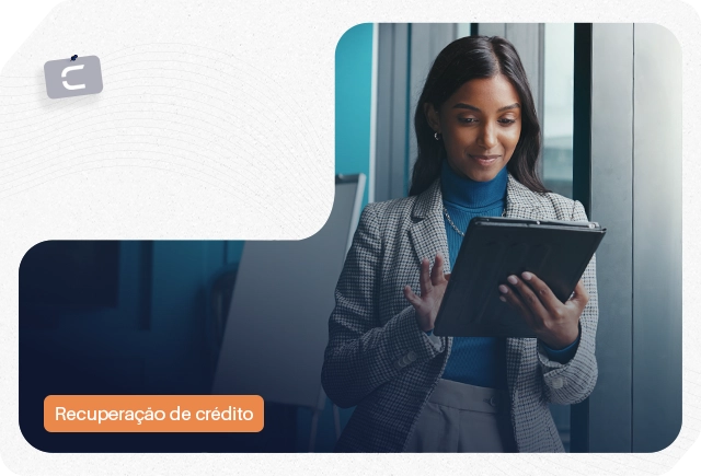 Mulher sorridente usa tablet em escritório com etiqueta 'Recuperação de crédito'.